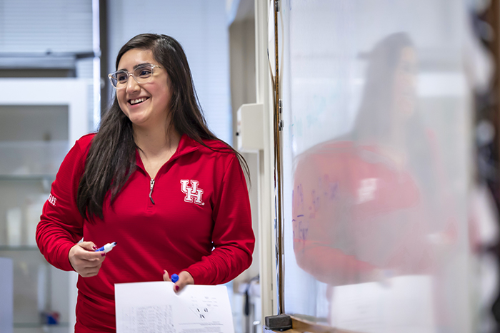 Woman with black hair and glasses in class waving her hand