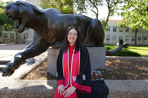 Woman with regalia sitting in front of a cougar statue