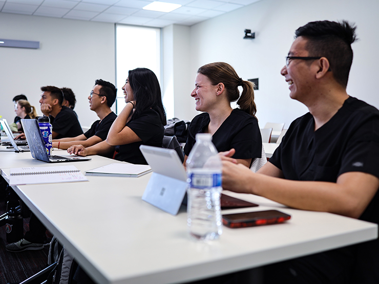 Students wearing black nursing uniforms sitting a desk