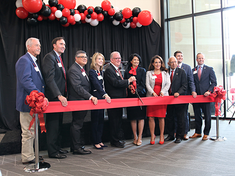 A group of people cutting a ribbon with scissors.