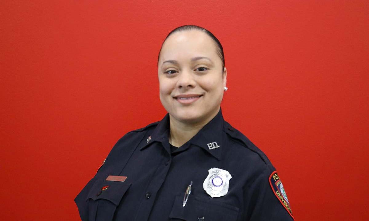 Portrait of a woman smiling in a navy blue police uniform.