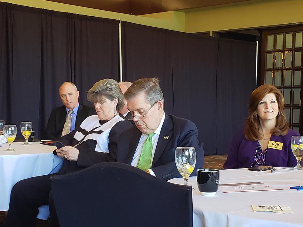 Men and women in business attire sitting at dining tables