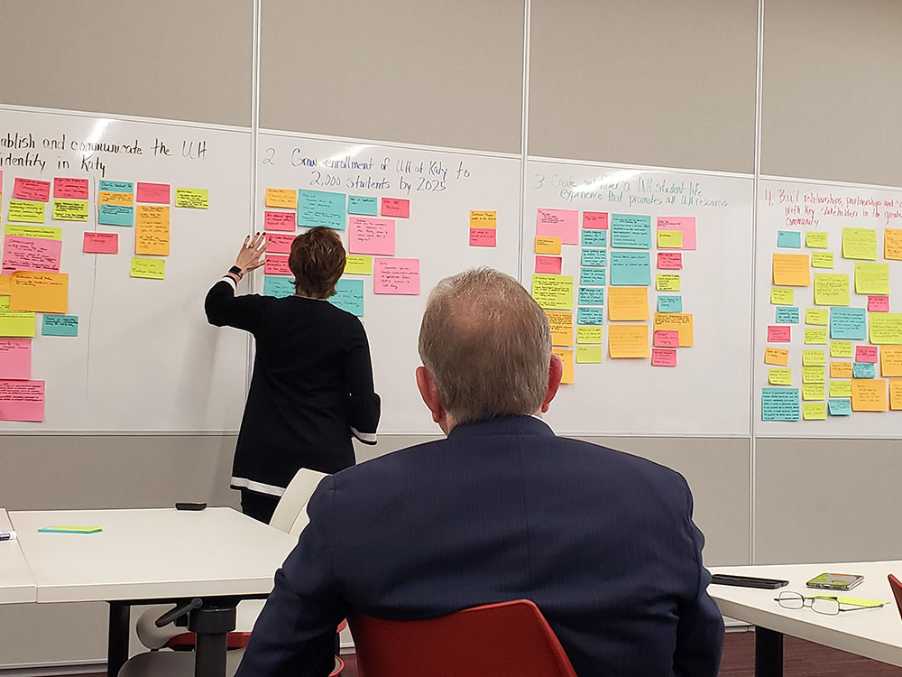 A woman places handwritten notes on a white board