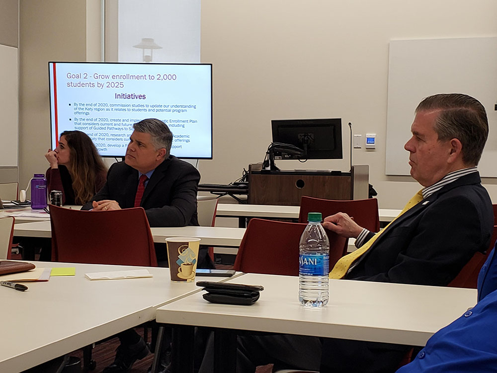 People sitting at tables looking to the left as they listen to a facilitator off-camera