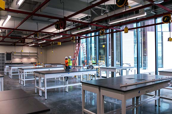 An almost completed classroom being constructed on by 2 workers