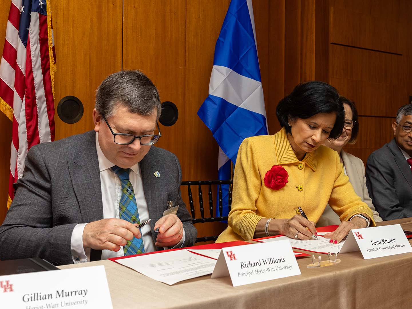 University of Houston President Renu Khator, in a yellow suit with red rose, and Heriot-Watt University's Principal Richard Williams, with glasses in a grey suit, signing agreement.