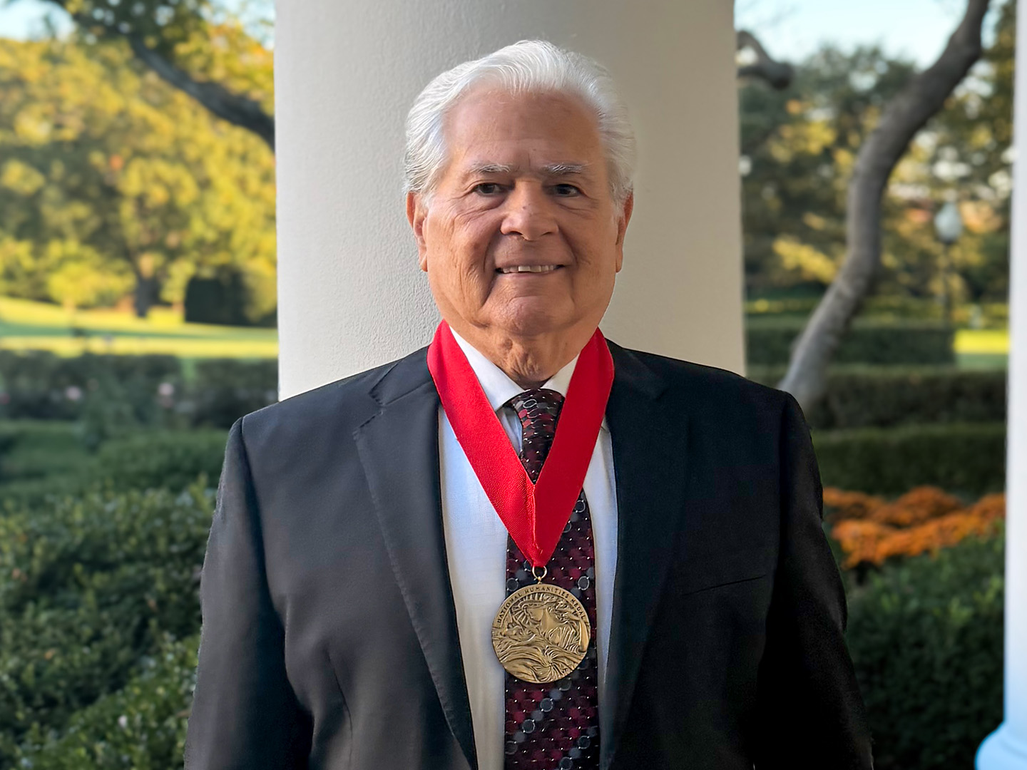 Nicolás Kanellos wearing a National Humanities Medal outside the White House.