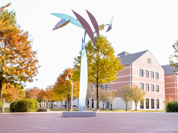 Metalic sculpture with trees and building in the background