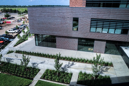 A bird's-eye view a courtyard surrounded by a dark-brown wall of bricks with large windows