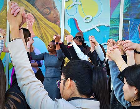 A diverse group of students lift their hands together at the Hands of Caring ceremony.