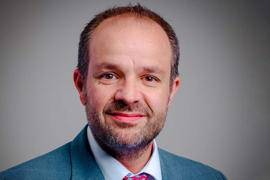 Portrait of a Hispanic man with a short faded beard in a blue business suit