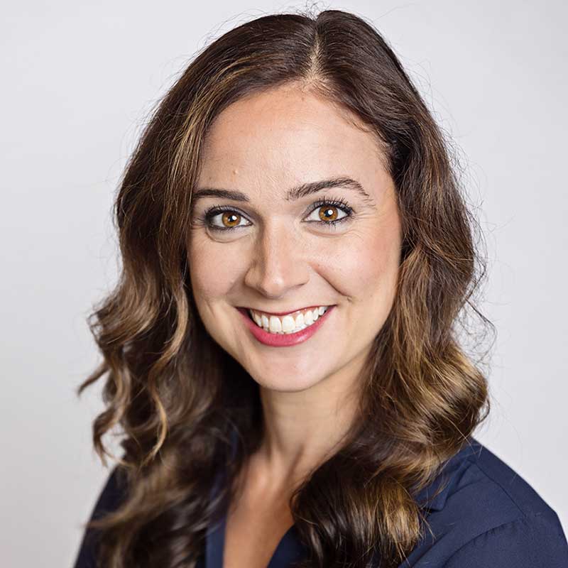 Portrait of a light brown-haired woman in a navy blue business blouse