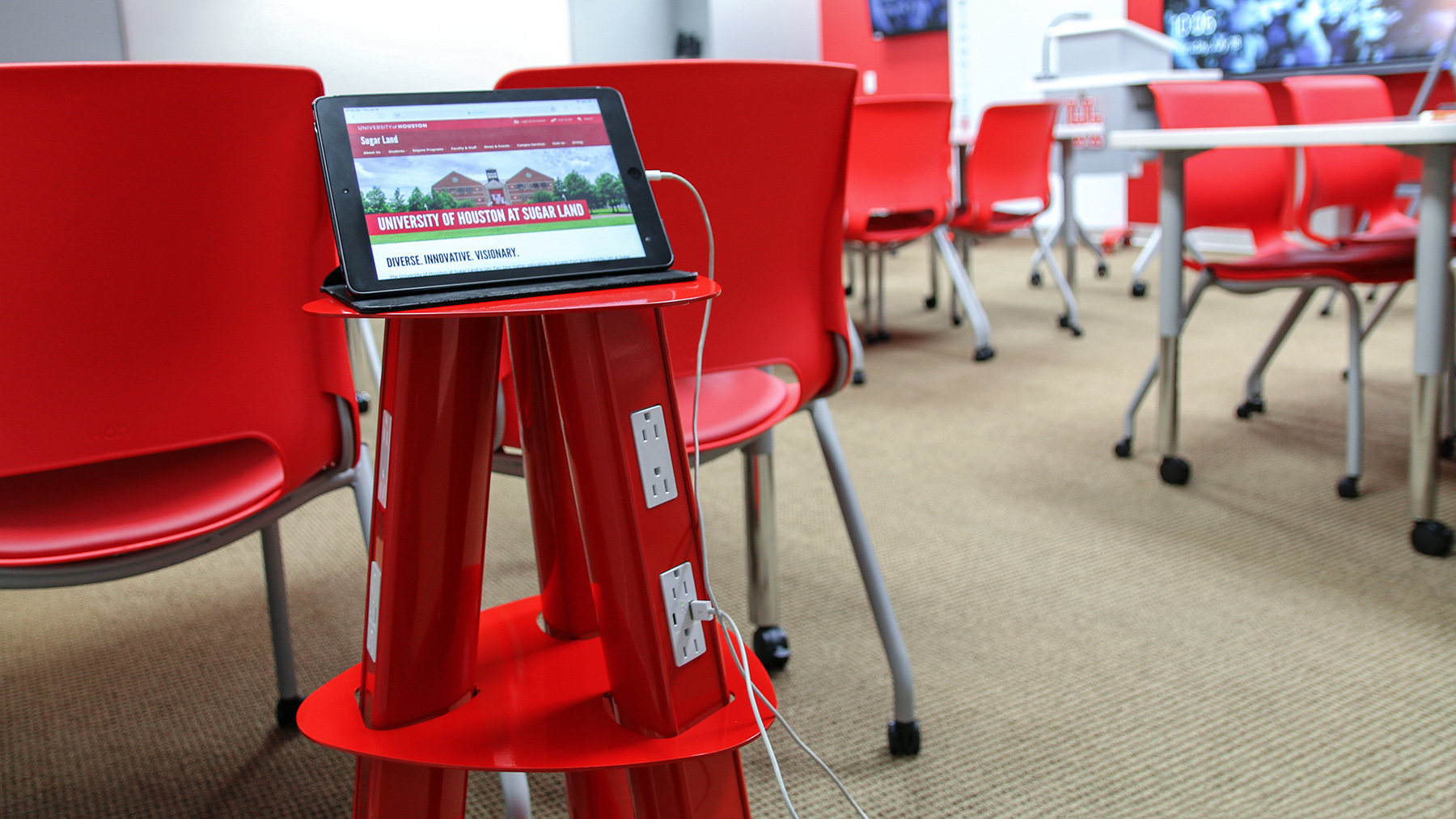 Closeup of a tablet plugged into a red portable charging station.