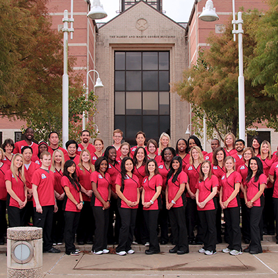 group of students in red and black uniforms standing in front a building